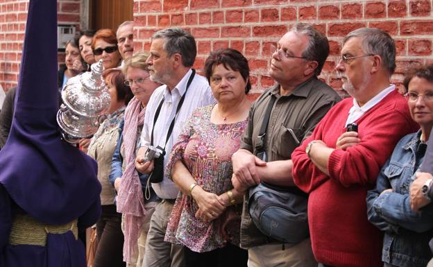 Turistas contemplan, impresionados, una procesión de Semana Santa en el centro de Málaga (archivo).