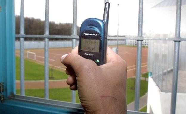 Un preso muestra un teléfono móvil dentro de la celda de una cárcel alemana. 