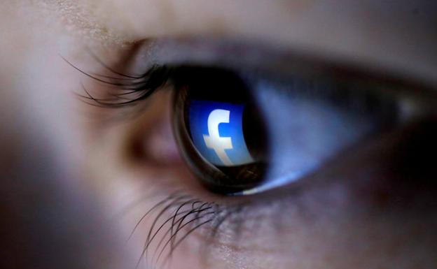 Reflejo del símbolo de Facebook en el ojo de una mujer. 