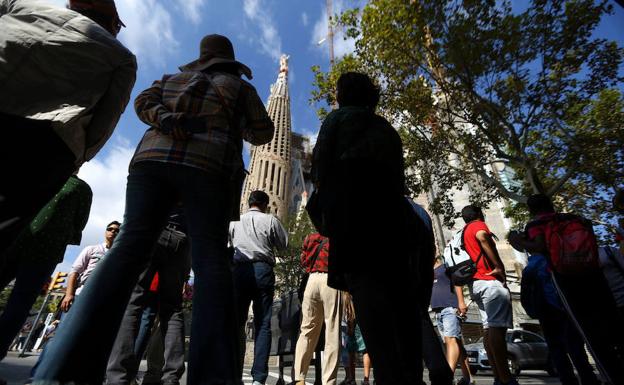 Varios turistas miran la basílica de la Sagrada Familia de Barcelona.