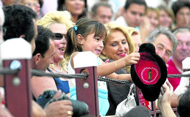 Una niña recoge la montera que le ha lanzado un torero en la plaza.