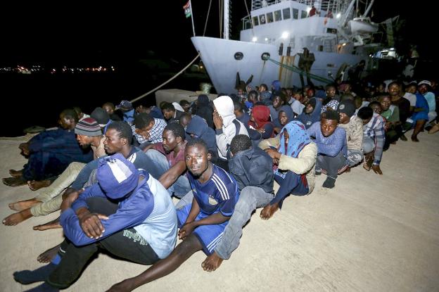 Un grupo de inmigrantes espera en la base naval de Trípoli, en Libia, tras ser rescatados en el Mediterráneo. :: mahmud turkia / afp