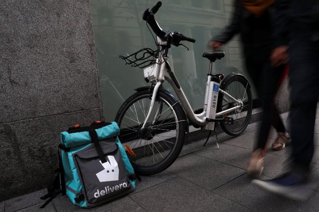 Una de las bicicletas que usan los repartidores de Deliveroo y la mochila con la comida a entregar. 