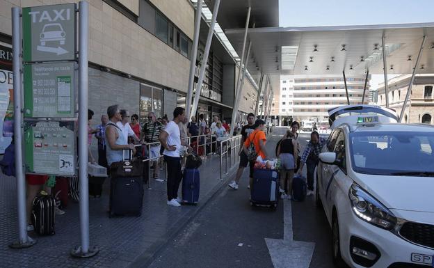 Viajeros esperan la llegada de taxis a la parada de la estación de trenes. 