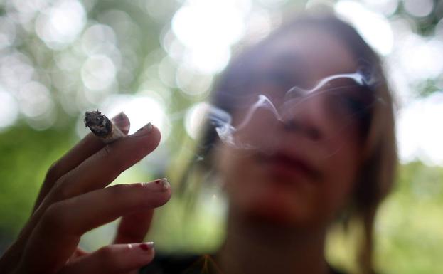 Una mujer fuma en un parque. 