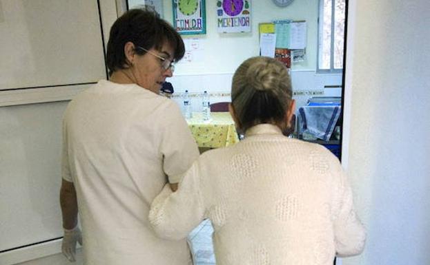 Una auxiliar acompaña a una enferma de alzhéimer en un Centro de Día.