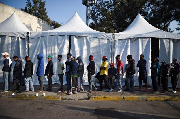 Un grupo de migrantes hace cola para ser atendido en uno de los estadios de Ciudad de México. ::  AFP