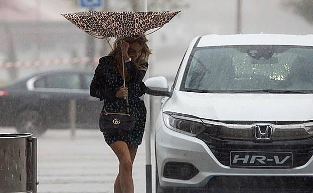 Una mujer trata de protegerse durante los recientes aguaceros. 