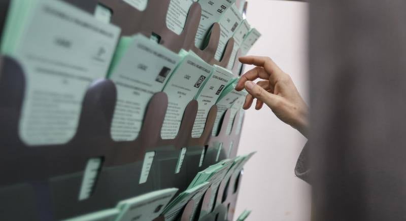 Una votante escoge la papeleta para elegir a su candidato hoy en el colegio electoral ubicado en la biblioteca de Sanlúcar de Barrameda(Cádiz)