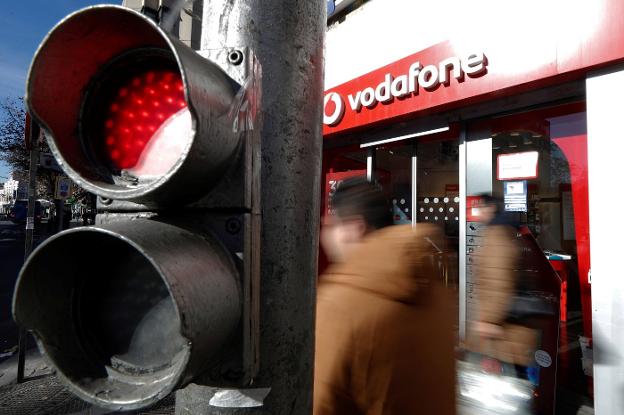 Varias personas pasan delante de una tienda de Vodafone en Madrid. :: j. lizón / EFE