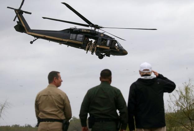 Trump, junto a miembros de la patrulla fronteriza de Texas, saluda al helicóptero que vigila Rio Grande. :: Leah Millis / reuters