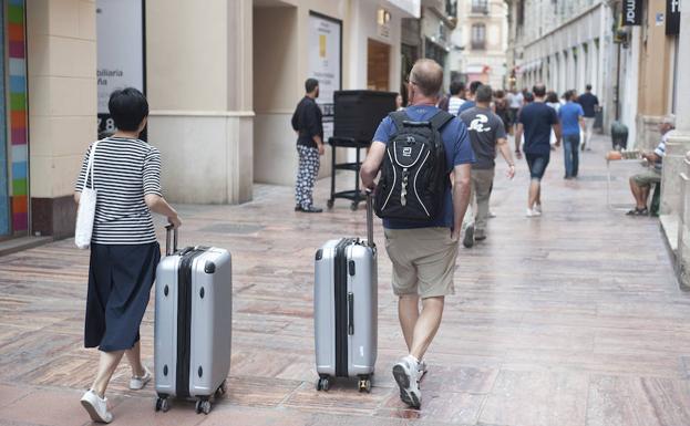 Turistas se dirigen, por el Centro Histórico de Málaga, hacia su alojamiento.