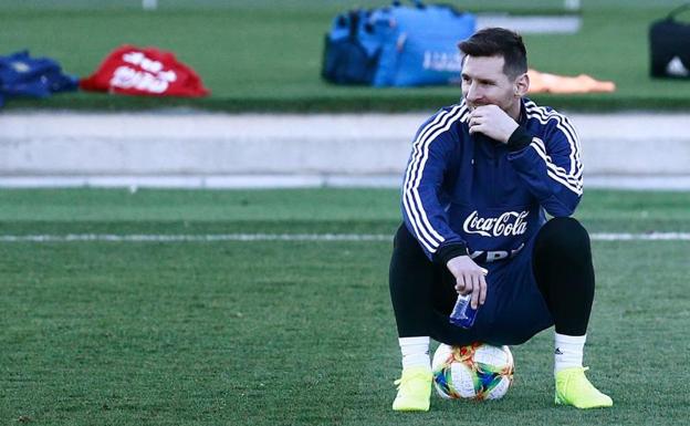 Messi sigue, sentando sobre un balón, el partidillo de sus compañeros con el que terminó el entrenamiento de la selección argentina. 