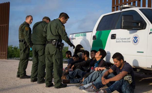 Los miembros de la Patrulla de Fronteras vigilan a un grupo de inmigrantes detenidos.