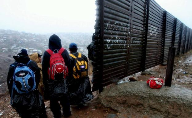 Un grupo de inmigrantes, en el vallado de la frontera de EE UU.