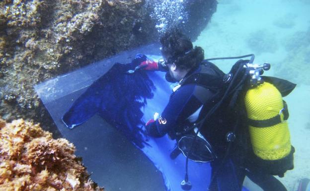 El artista Alfonso Cruz interviniendo un traje de Manuel Fernández bajo el mar.