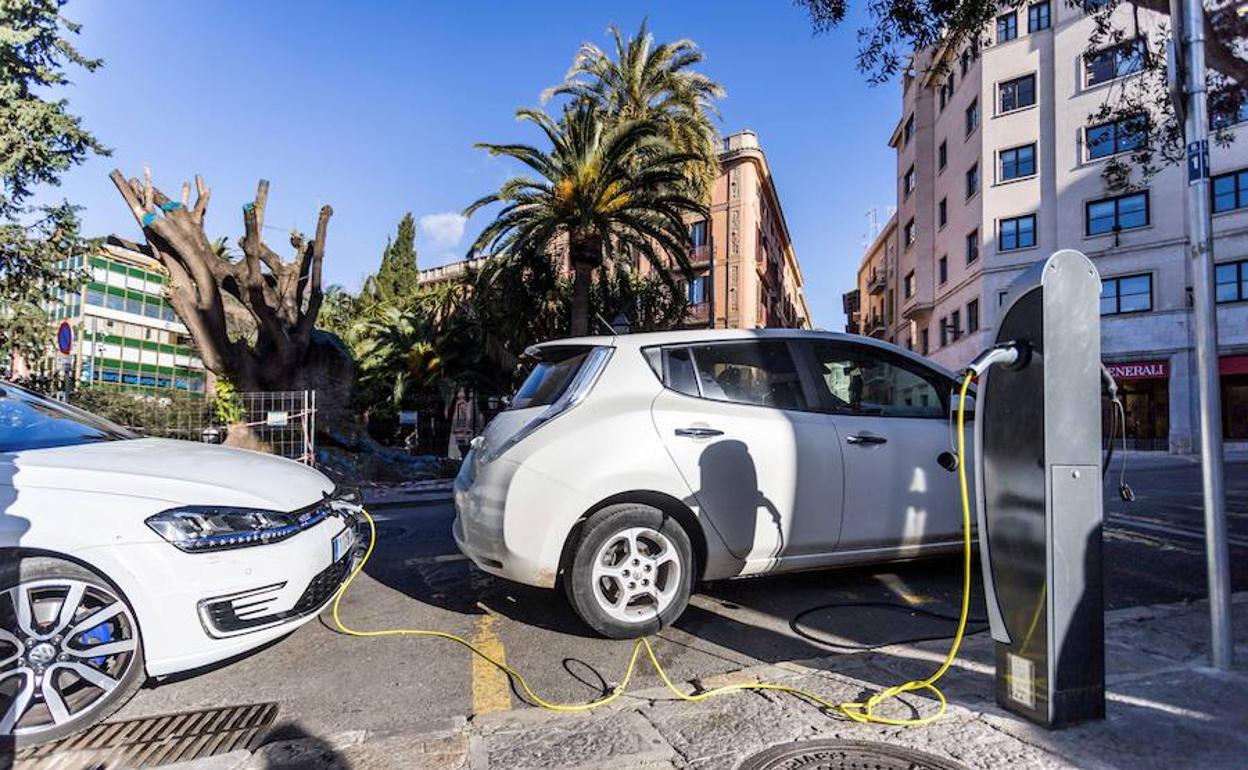 Coches eléctricos cargando en un poste en la calle. 