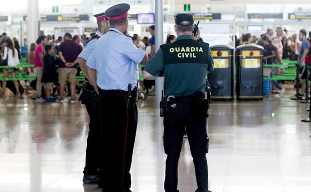 Agentes de la Guardia Civil y de los Mossos d'Esquadra trabajan en el área de control de seguridad de Aeropuerto de El Prat. 