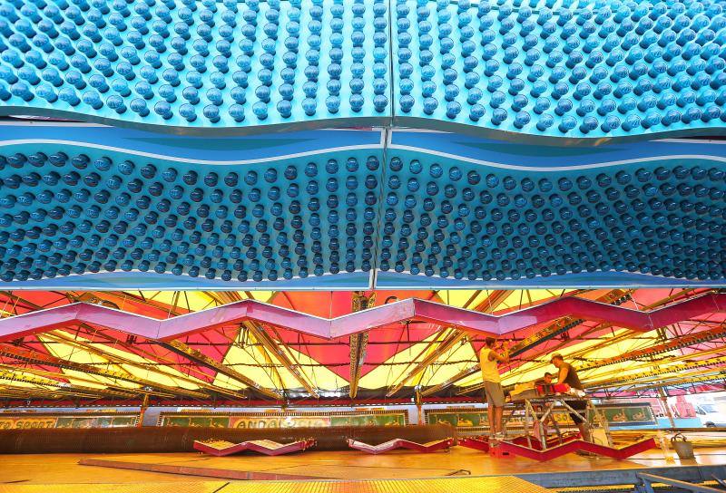 Feriantes, operarios municipales y de contratas y peñistas llevan semanas afanados en poner a punto todos los elementos que conforman esa ciudad efímera que es el Real de Cortijo de Torres.