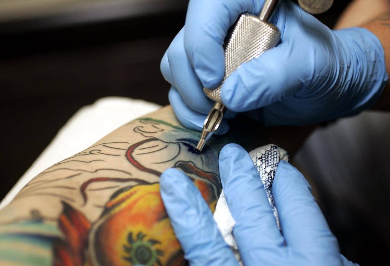 Un tatuador trabaja sobre un brazo. :: sur