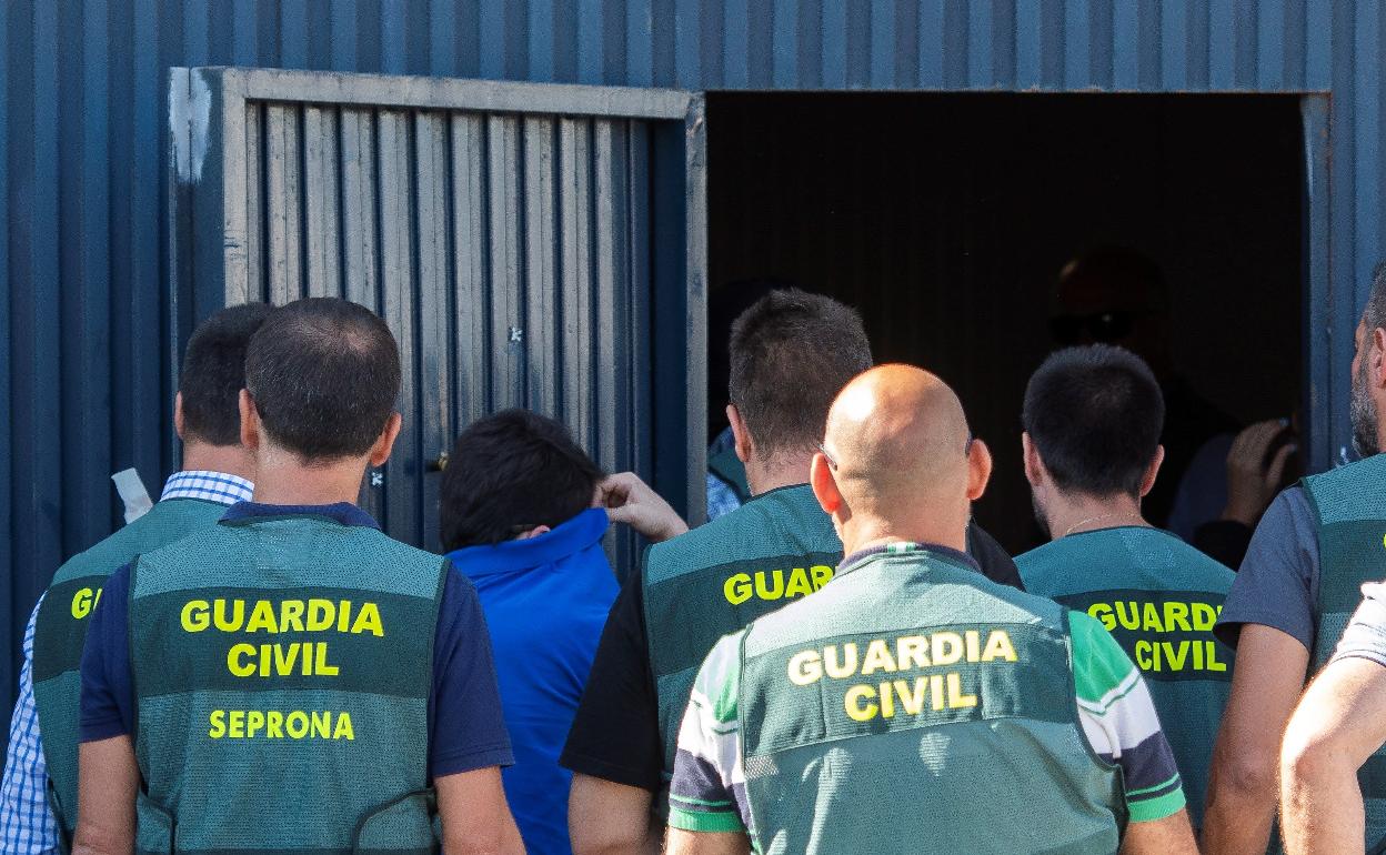 Efectivos de la Guardia Civil con uno de los detenidos, durante el registro del martes. 