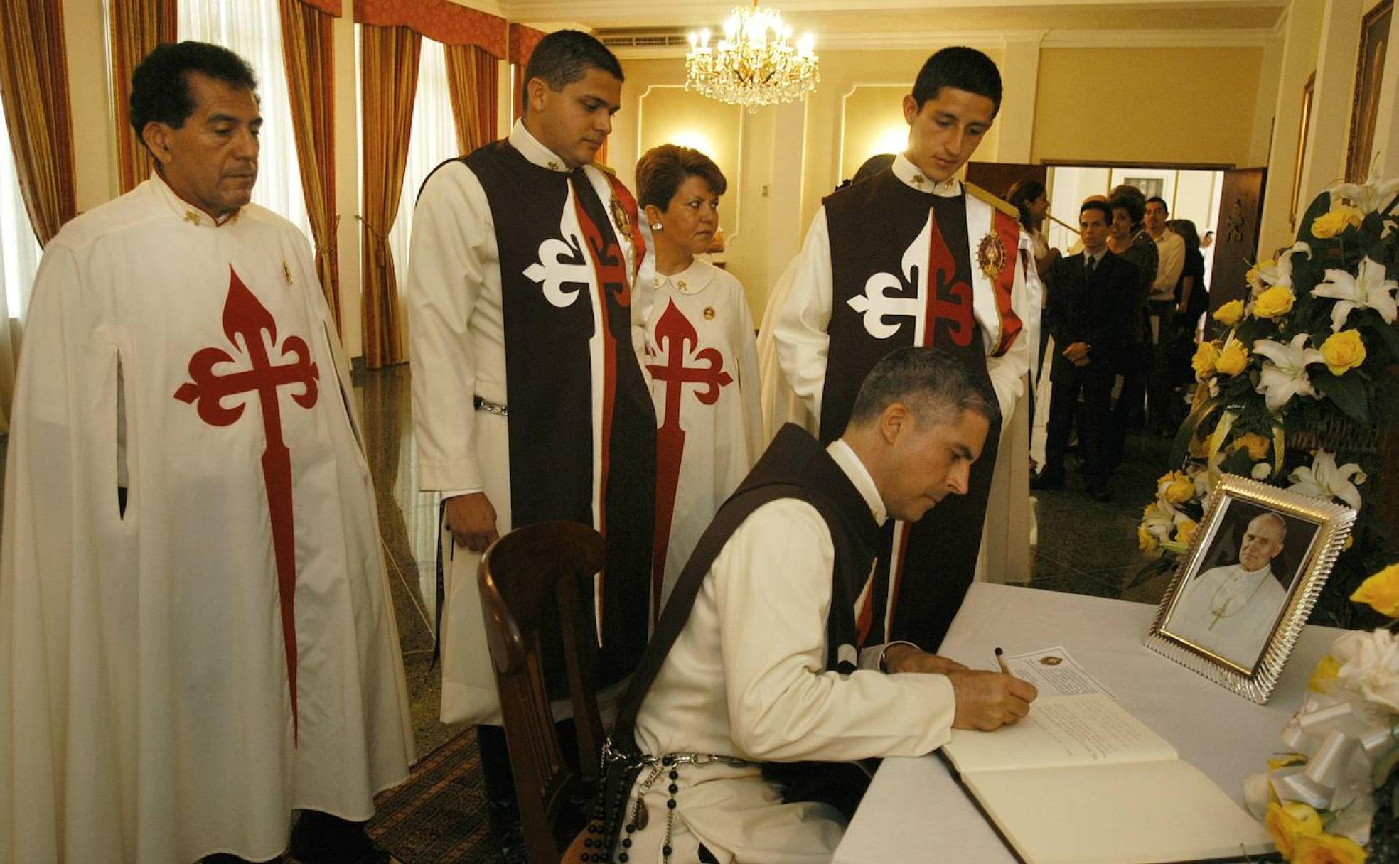 Miembros del movimiento Heraldos del Evangelio firman en un libro de honor ante una imagen de Juan Pablo II, su valedor. 