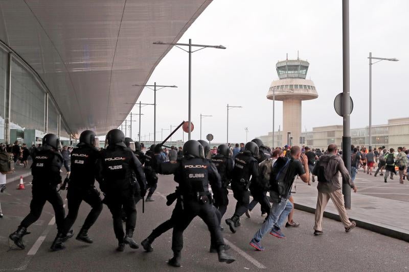 Miembros de los Mossos d'Esquadra cargan contra los centenares de personas que se agolpan ante el Aeropuerto del Prat 