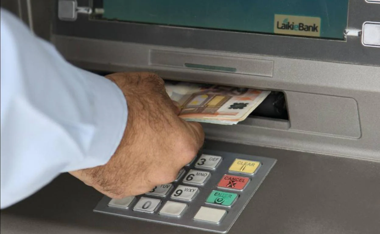 Imagen de archivo de una persona sacando dinero de un cajero.