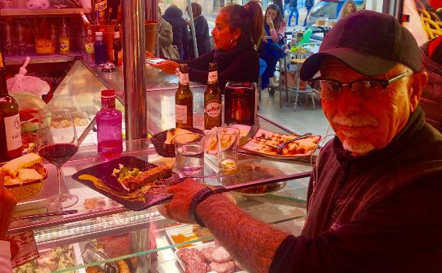 Imagen principal - Arriba, el actor y motero George Christie, en el mercado de Atarazanas. Abajo, junto a la catedral de Málaga y señalando una foto de Orson Welles en La Farola de Orellana.