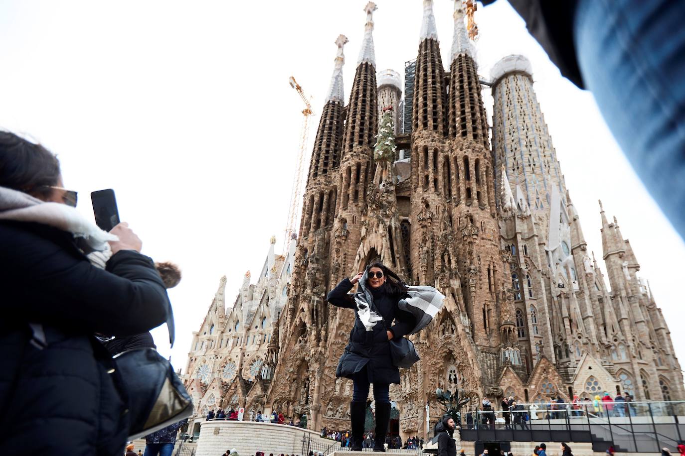 Turistas se fotografían ante la Sagrada Familia bajo un fuerte viento, en Barcelona