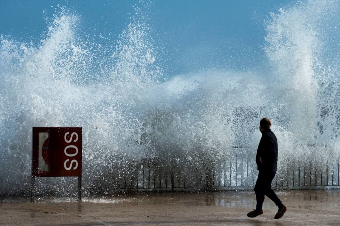 Una persona observa las grandes olas en la playa de la Barceloneta, en Barcelona