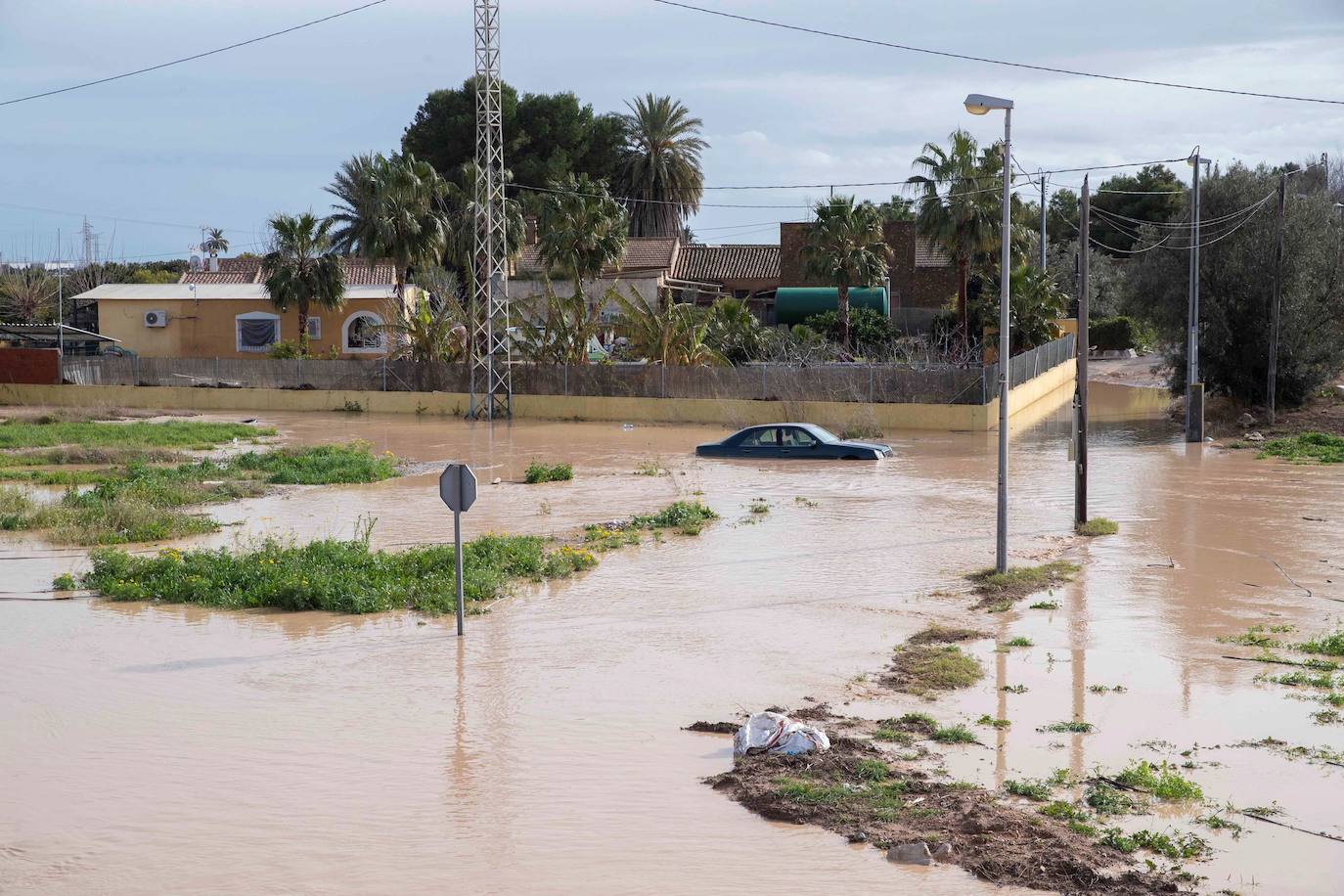 Un coche atrapado junto a una vivienda a causa del desbordamiento de la rambla de la Maraña de San Javier, tras las intensas lluvias en el campo de Cartagena. 