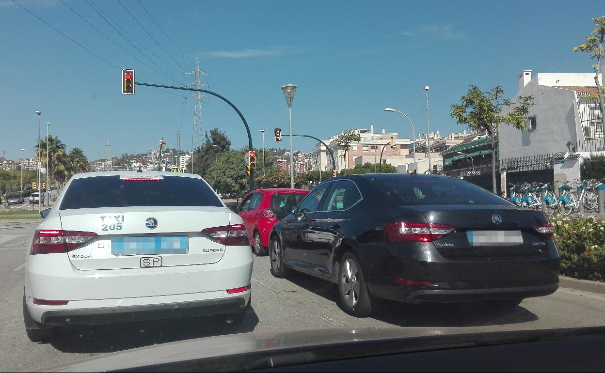 Un taxi y un vehículo de VTC circulando en paralelo por una calle de Málaga. 