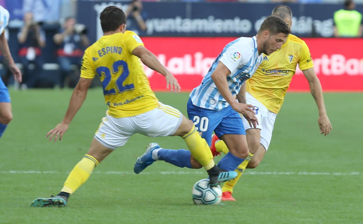 Keko intenta marcharse de dos contrarios durante un partido del Málaga.