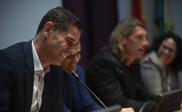 Fernando Hierro, sonriente en primer plano, con Herrmann al fondo. 