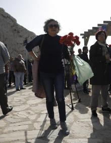 Imagen secundaria 2 - La imagen superior muestra a los asistentes al acto de homenaje en el lugar de la placa conmemorativa a las víctimas de la carretera Málaga-Almería. Por debajo, unas rosas flotando en la orilla y una mujer que ha acudido al acto. 