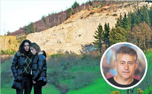 Gema y Bego, hermanas de Joaquín, se abrazan en el barrio de Eitzaga, en Zaldibar. Al fondo, se observa parte de la avalancha ocasionada por el colapso del vertedero.