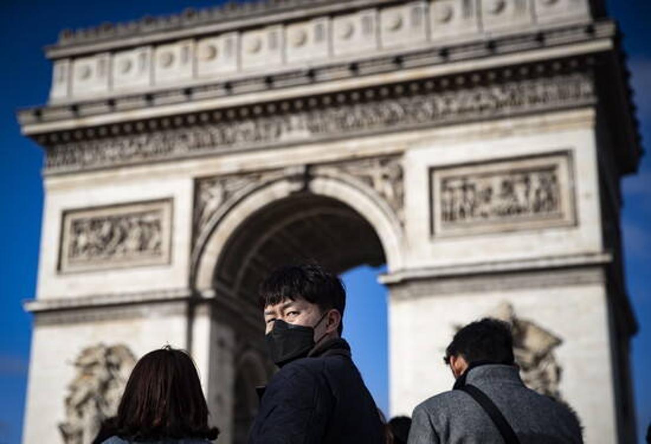 Un turista usa una máscara protectora frente al Arco del Triunfo en los Campos Elíseos en el centro de París