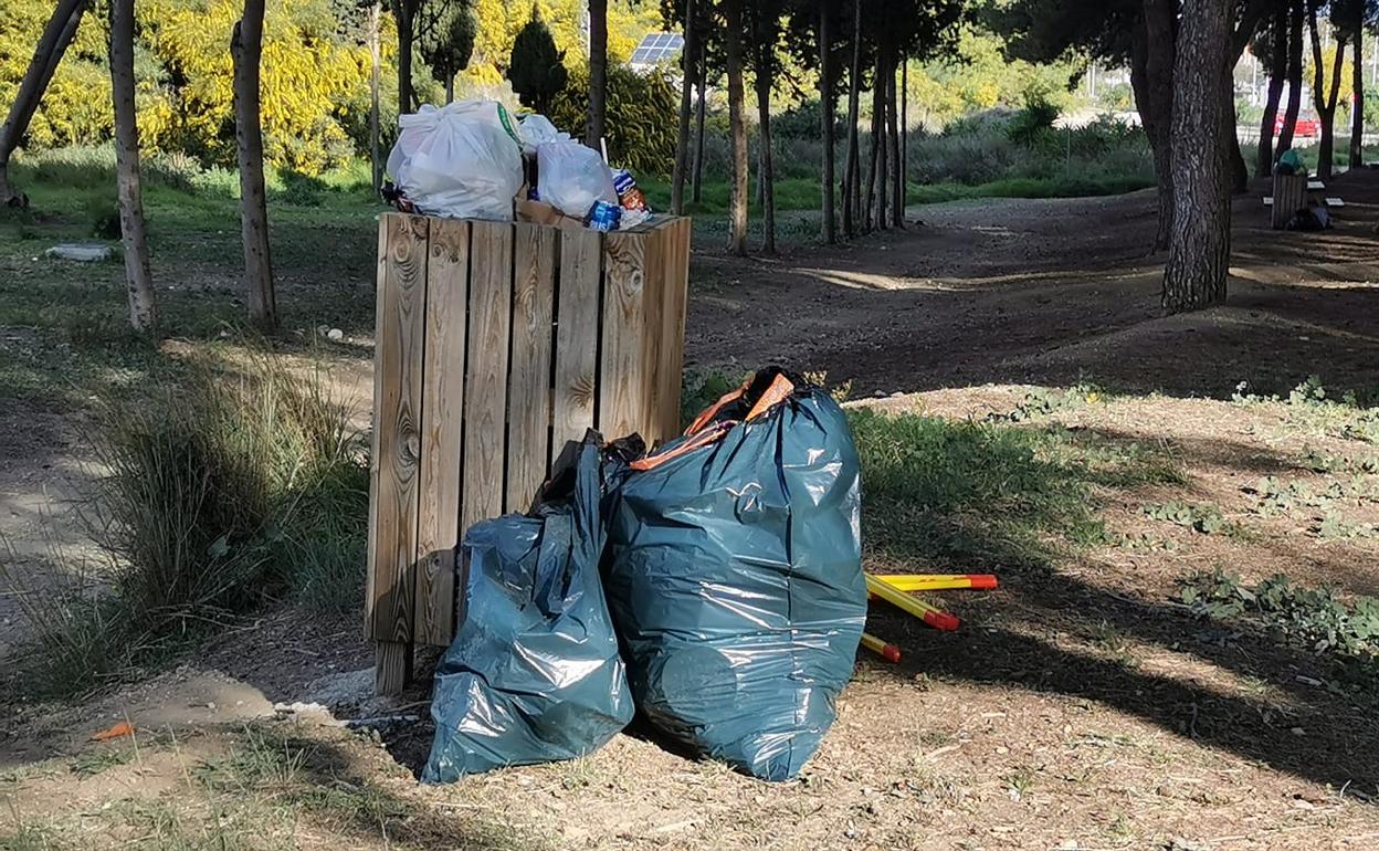 Papelera llena a primera hora de la mañana con bolsas de basura alrededor.