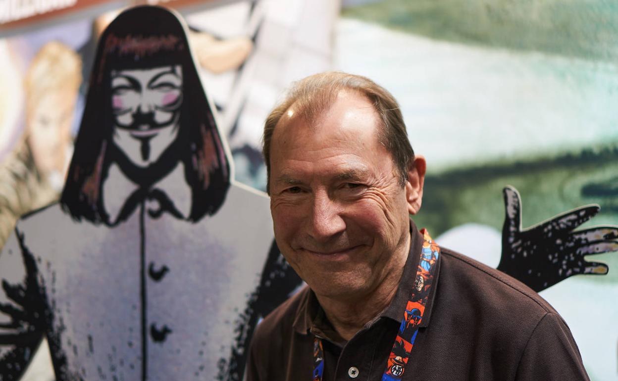 David Lloyd posa junto a un cartel del personaje de 'V de Vendetta', cómic que creó junto a Alan Moore.
