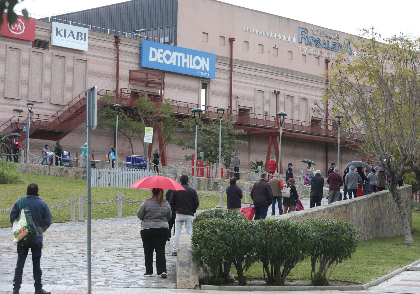 Ciudadanos hacen cola para acceder al centro comercial Rosaleda, en Málaga capital.