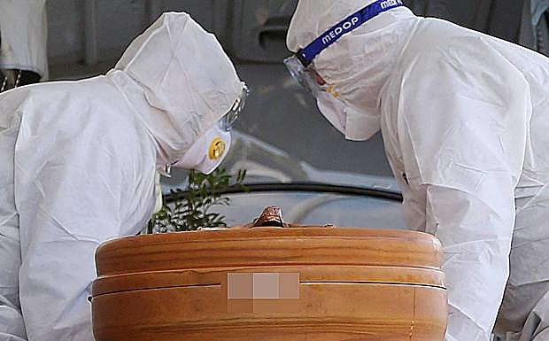 Operarios trasladan un féretro. 