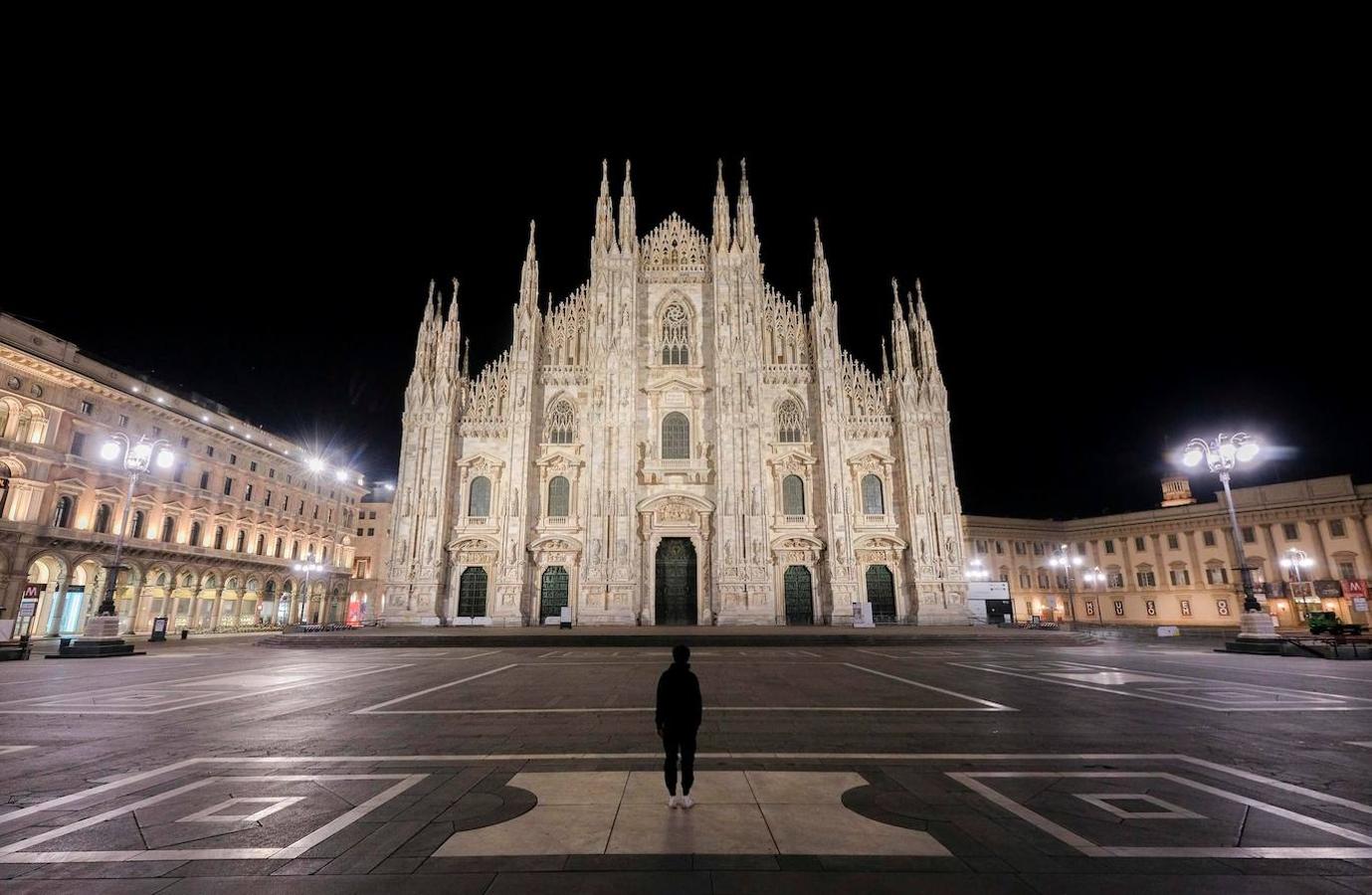 Una persona observa el Duomo de Milán desde la plaza totalmente vacía.