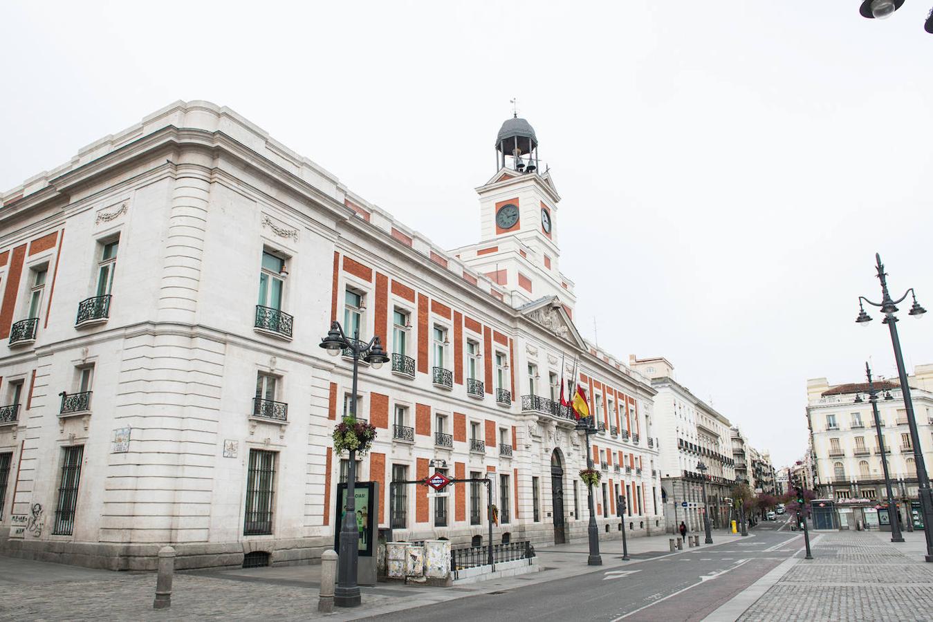 Fachada del Ayuntamiento de Madrid con las banderas a media asta durante el minuto de silencio en el primer día del luto oficial por los fallecidos del COVID-19.