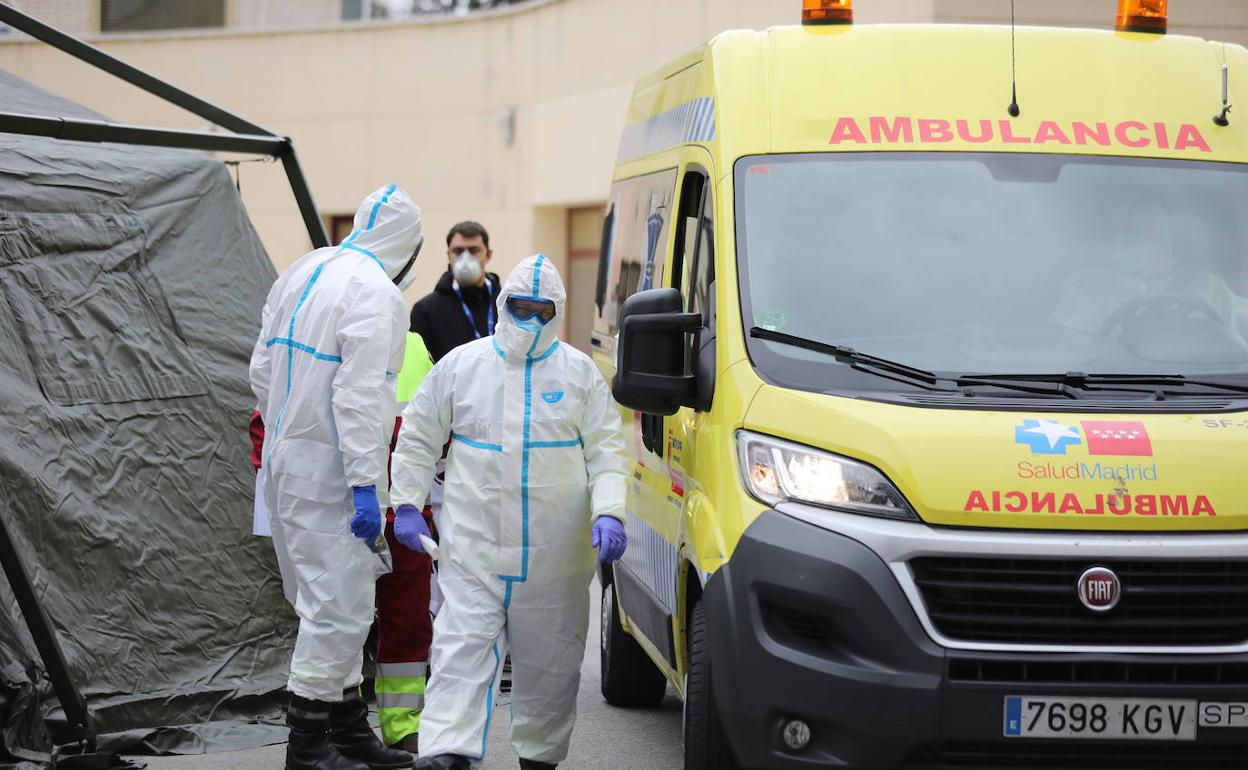 Sanitarios completamente protegidos acceden a una ambulancia. 