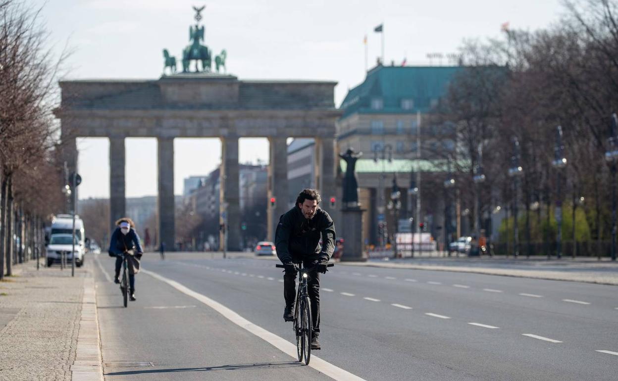 Dos ciclistas con la Puerta de Brandemburgo al fondo, en Berlín.