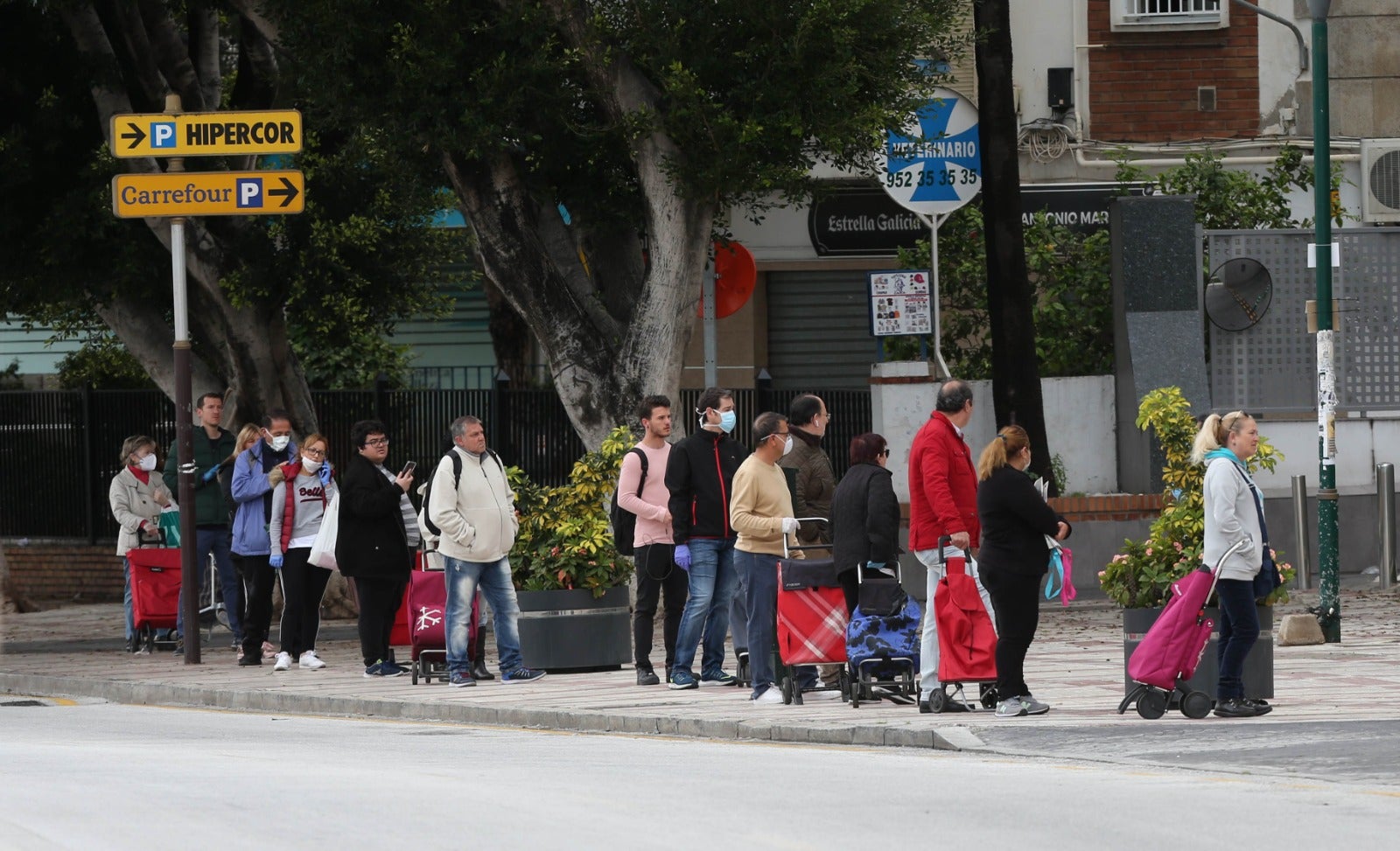 Un grupo de personas hacen cola a las puertas de un supermercado.
