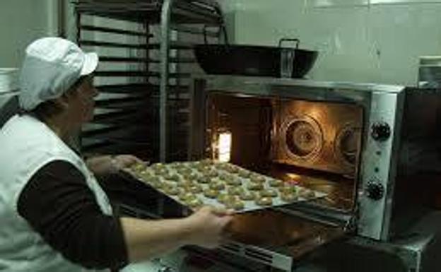 Rosario Ginés introduce una bandeja de pan de cortijo en el horno.