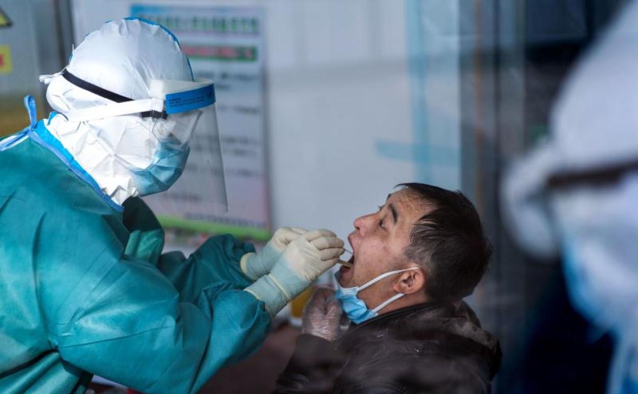 Un sanitario de un centro de salud de Suifenhe, en China, toma muestras a un hombre. 