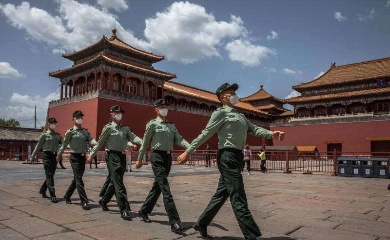 Soldados del Ejército Popular de Liberación de China con máscarillas protectoras marchan más allá de la entrada a la Ciudad Prohibida, en Beijing.